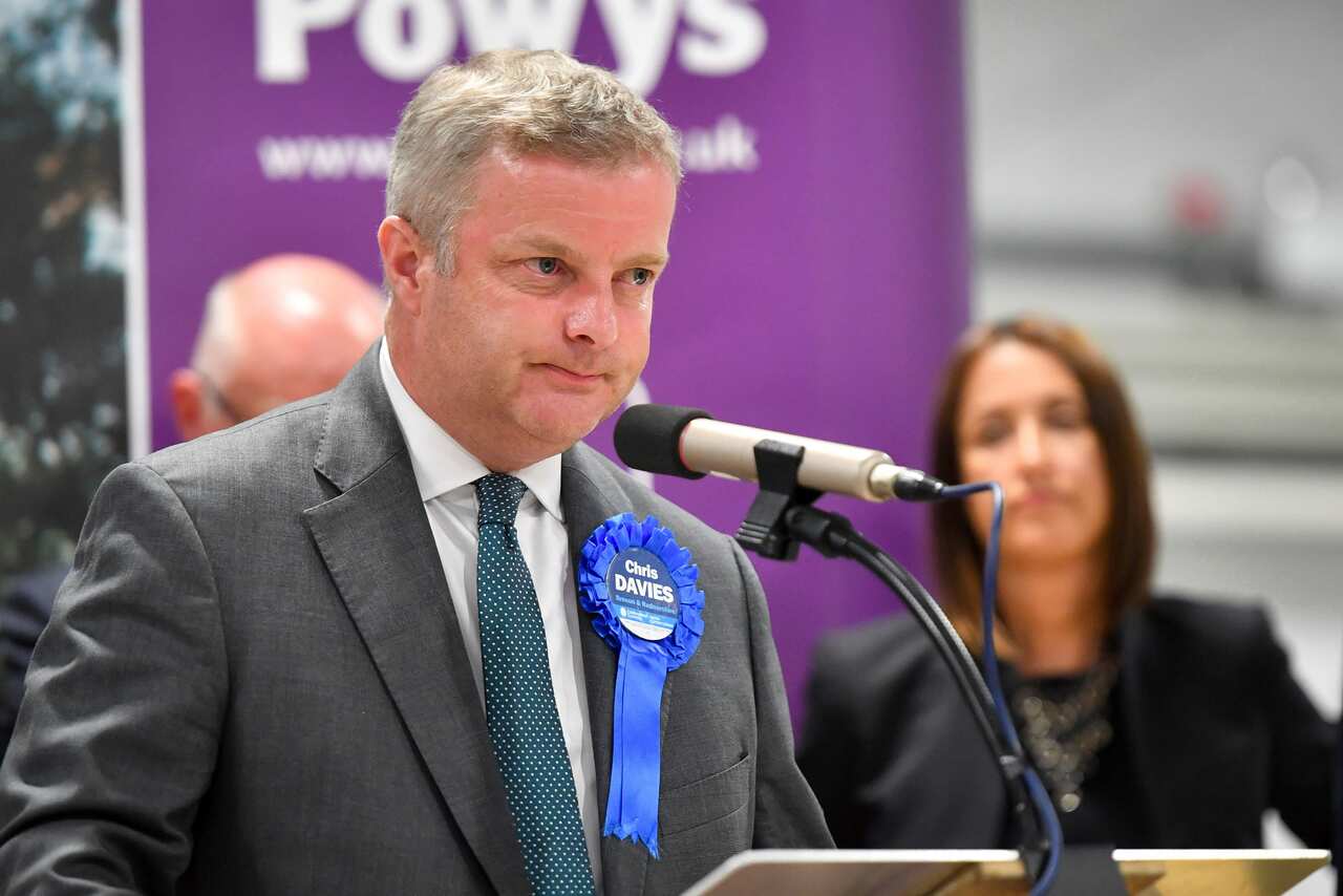 Conservative Chris Davies speaks on stage as Liberal Democrats MP Jane Dodds looks on after winning the seat in the Brecon and Radnorshire by-election.