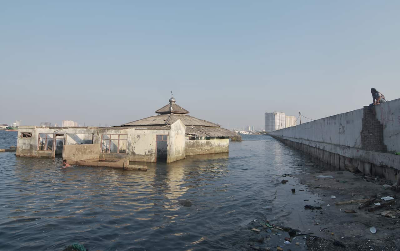 Local abandoned mosque stands beyond the seawall in the Muara Baru area in Jakarta.