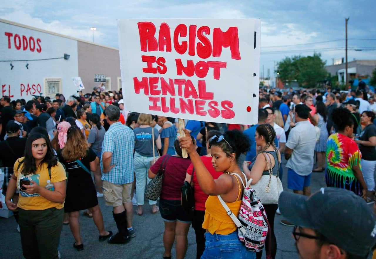 A woman holds a sign after a silent march to Las Americas Immigrant Advocacy Center for the victims of the Walmart shootings in El Paso.