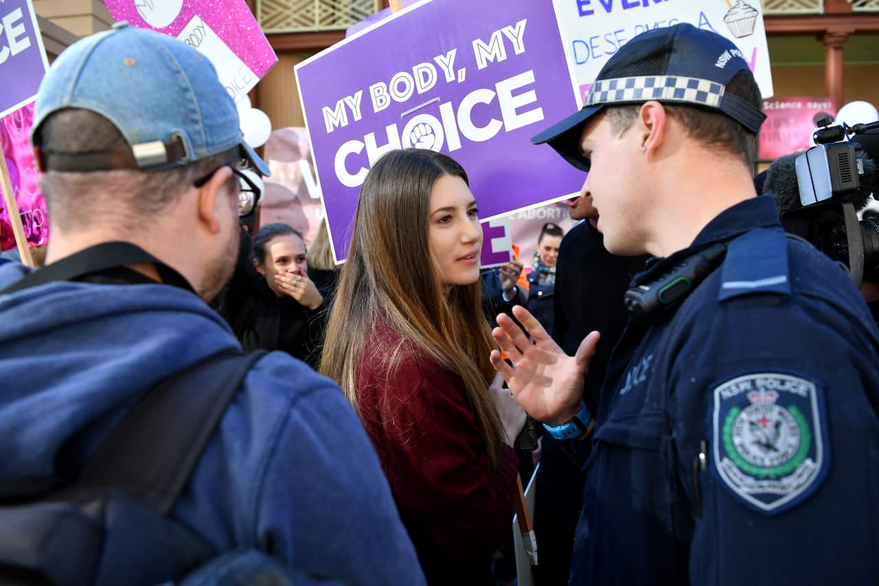 NSW Police speak to a woman during a rally outside the New South Wales Parliament house in Sydney, Tuesday, August 6, 2019. (AAP Image/Joel Carrett) NO ARCHIVING