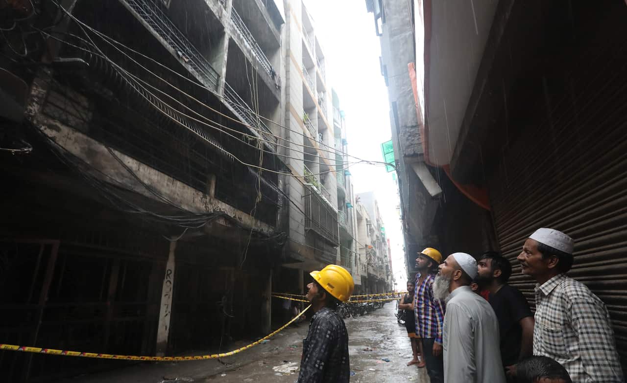 People stand on a street where a residential building fire broke out in New Delhi.