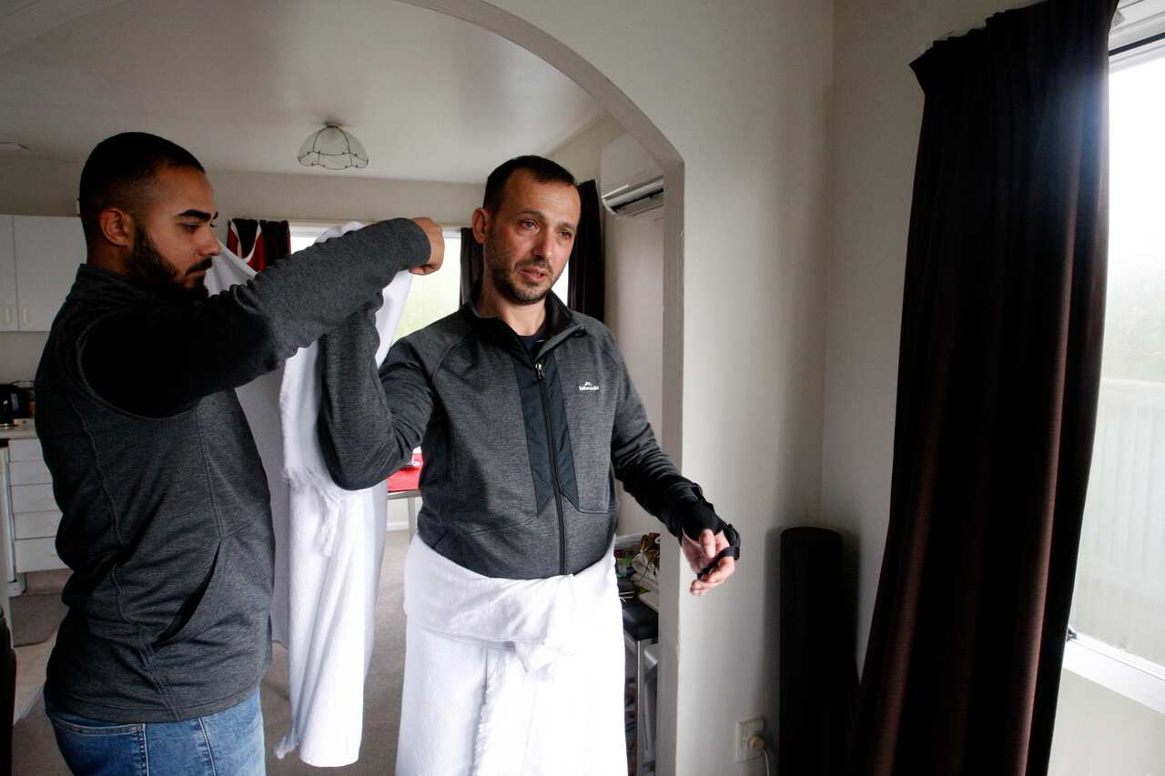 Temel Atacocugu, who was shot nine times during the Christchurch mosque attacks, tries on the clothes he will wear during the Hajj pilgrimage.