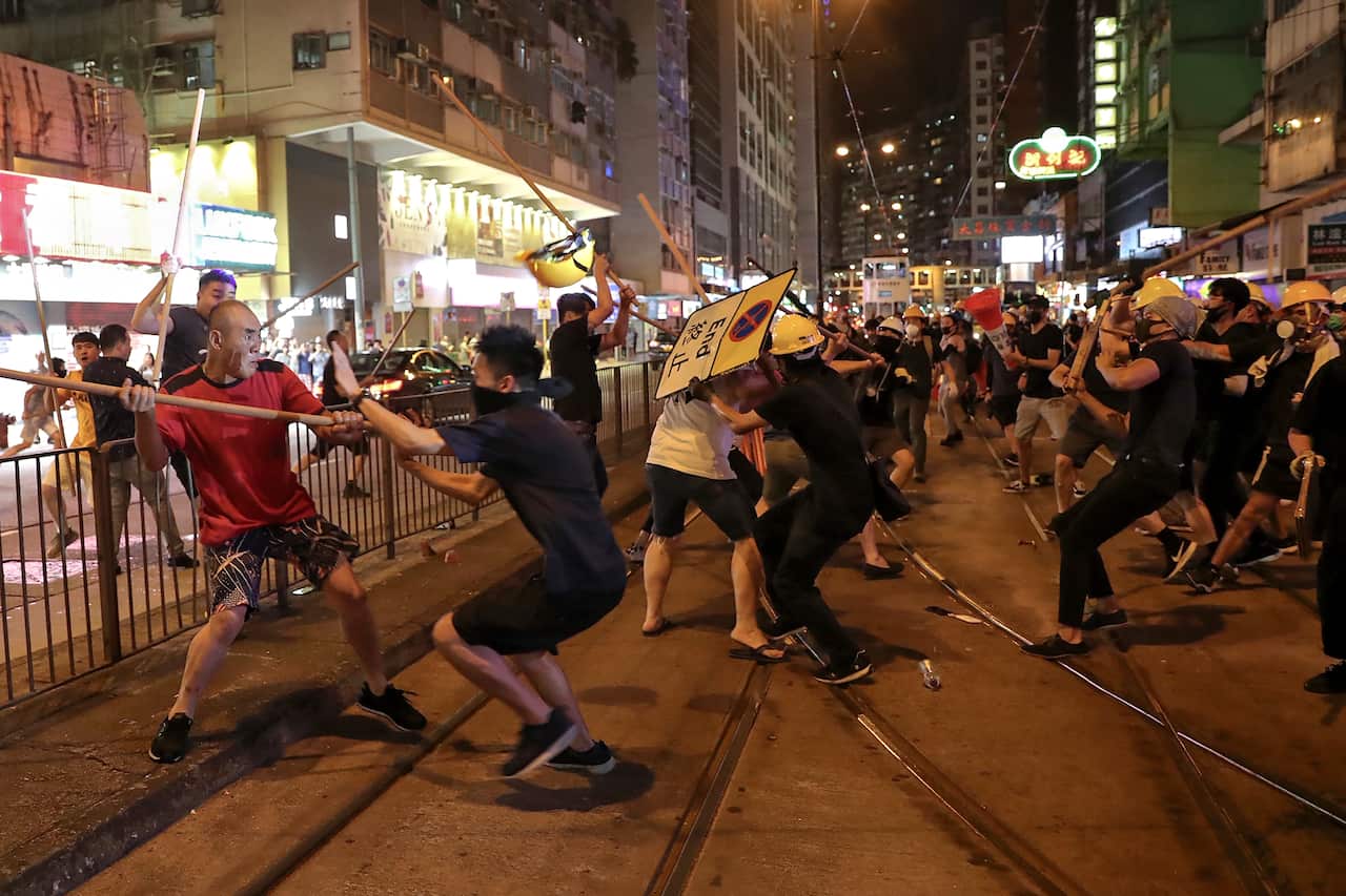 Protesters fight with a group of men wielding wooden poles on a Hong Kong street.