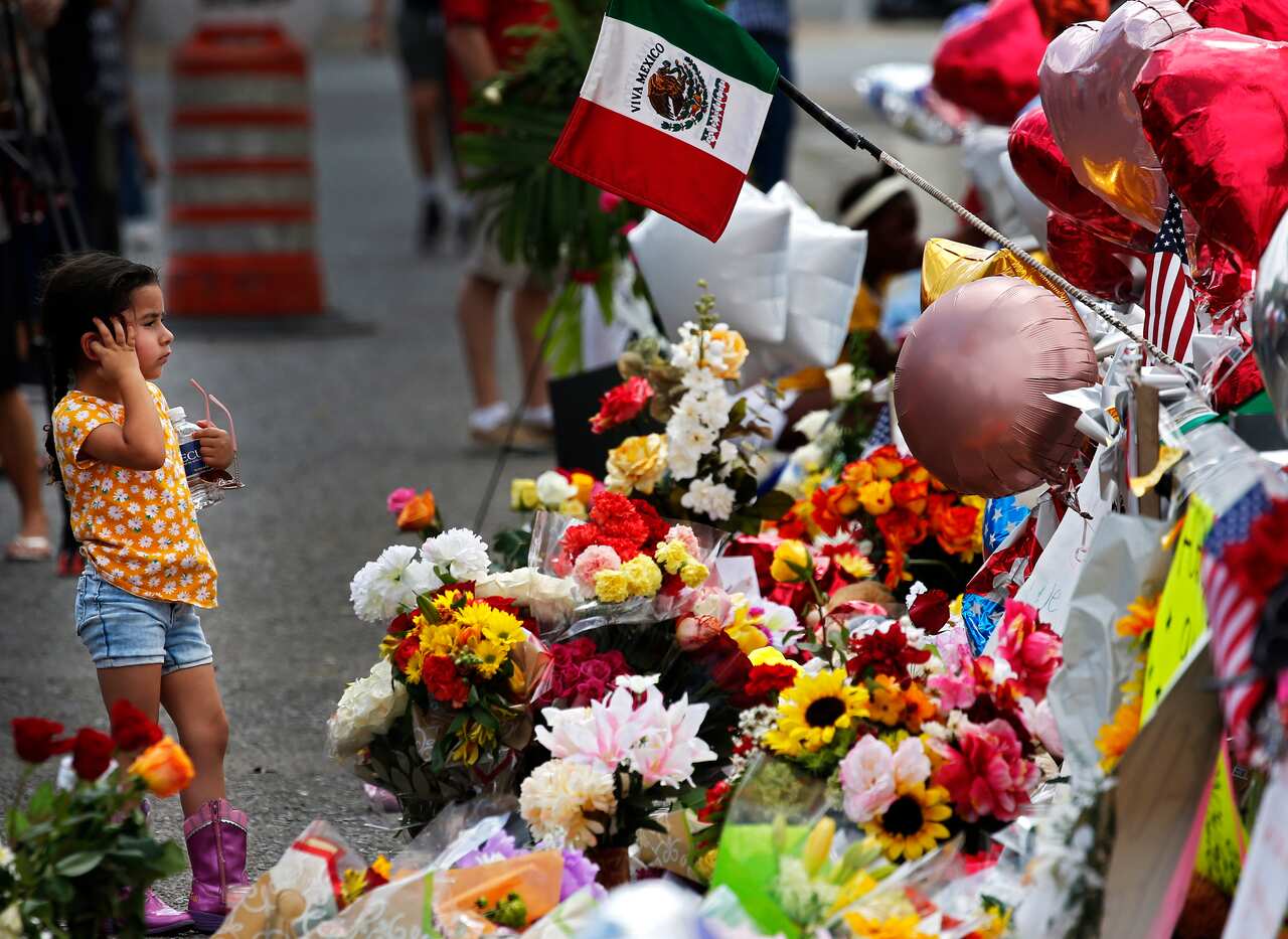 A little girl pauses to look at flowers at the make shift memorial after the Walmart mass shooting in El Paso, Texas.