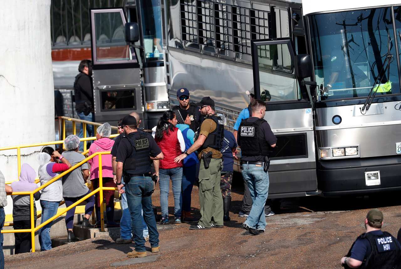 Handcuffed female workers begin to climb into a bus for transportation to a processing center following the raid.
