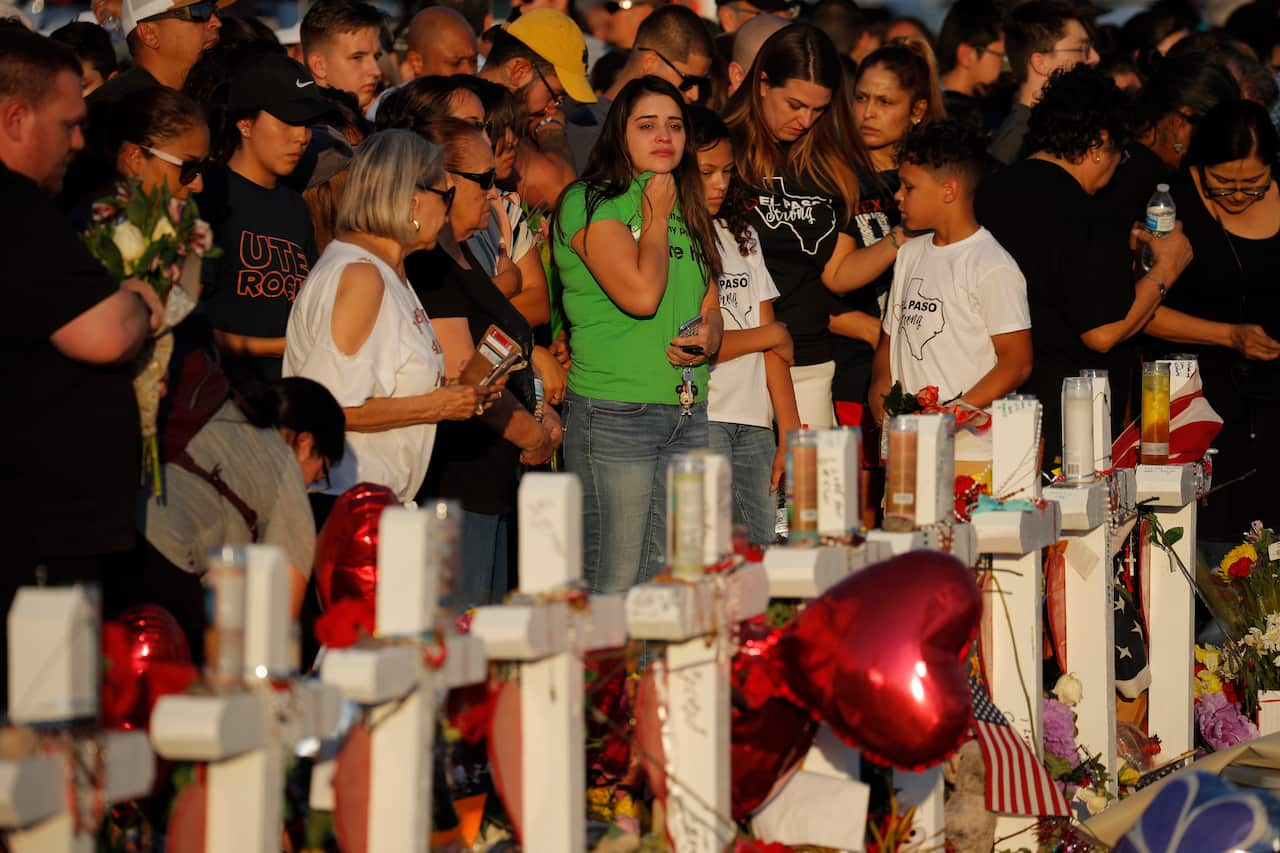 People visit a makeshift memorial at the scene of a mass shooting at a shopping complex in El Paso, Texas.
