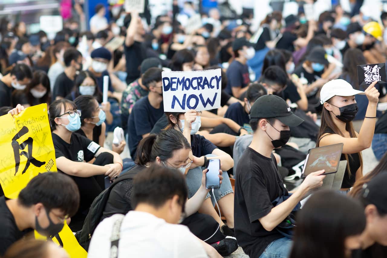 A protester holds a placard reads "Democracy now" during the demonstration in the airport.