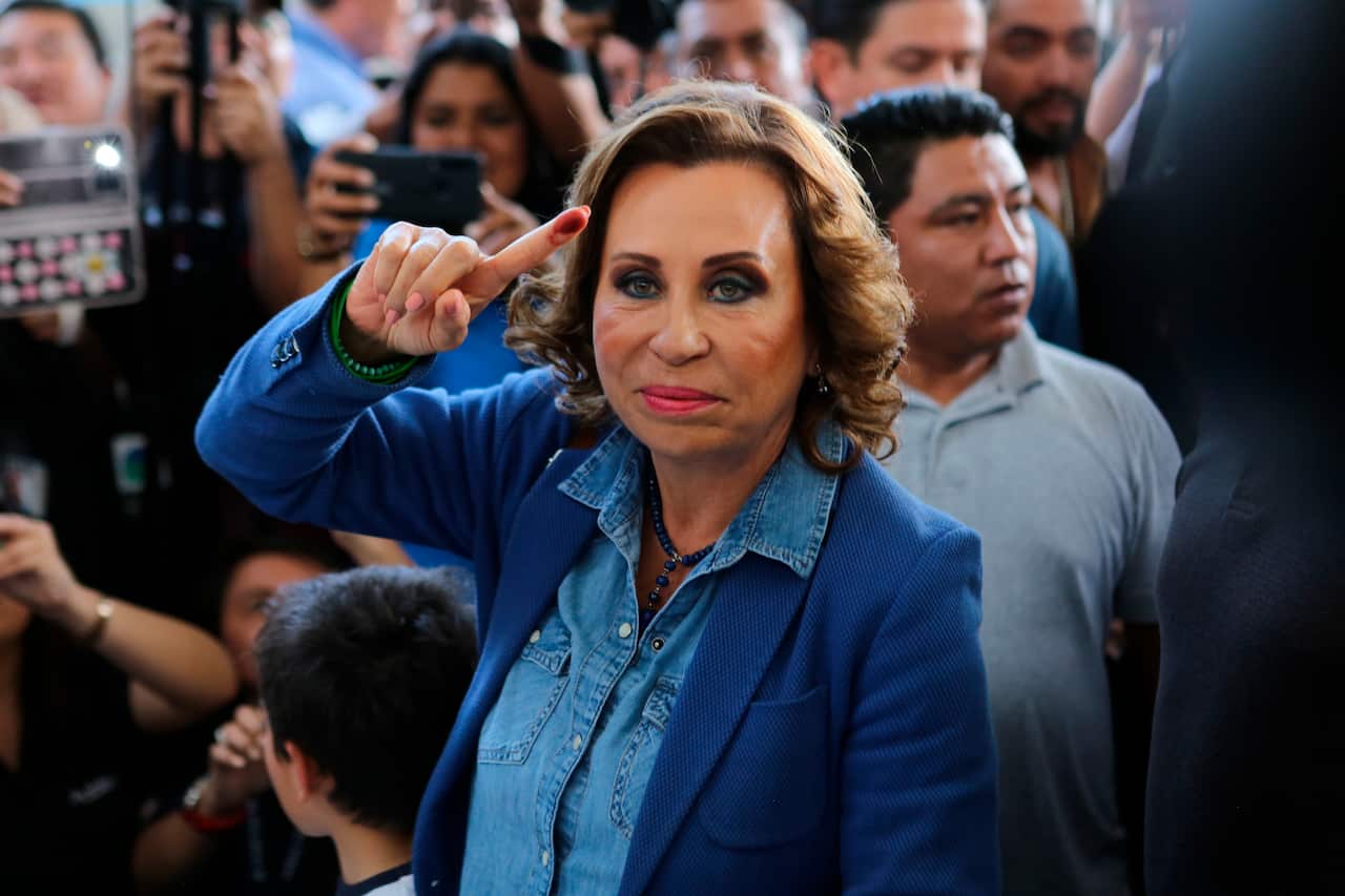 Former first lady turned presidential candidate Sandra Torres shows her ink-stained finger after casting her vote.