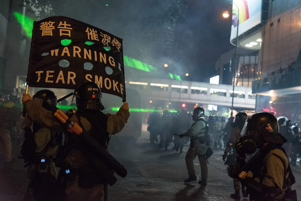Riot police fire tear gas near a shopping center.