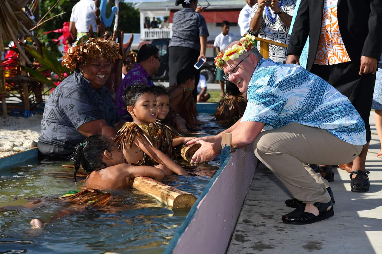 Children symbollically represent climate change greet Prime Minister Scott Morrison as he arrives for the Pacific Islands Forum in Funafuti, Tuvalu.