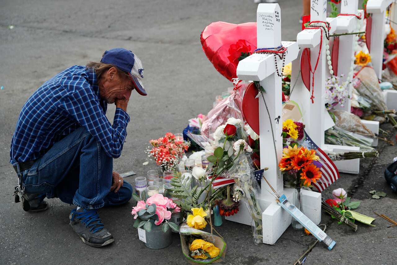Antonio Basco cries beside a cross at a makeshift memorial near the scene of a mass shooting at a shopping complex, in El Paso, Texas.