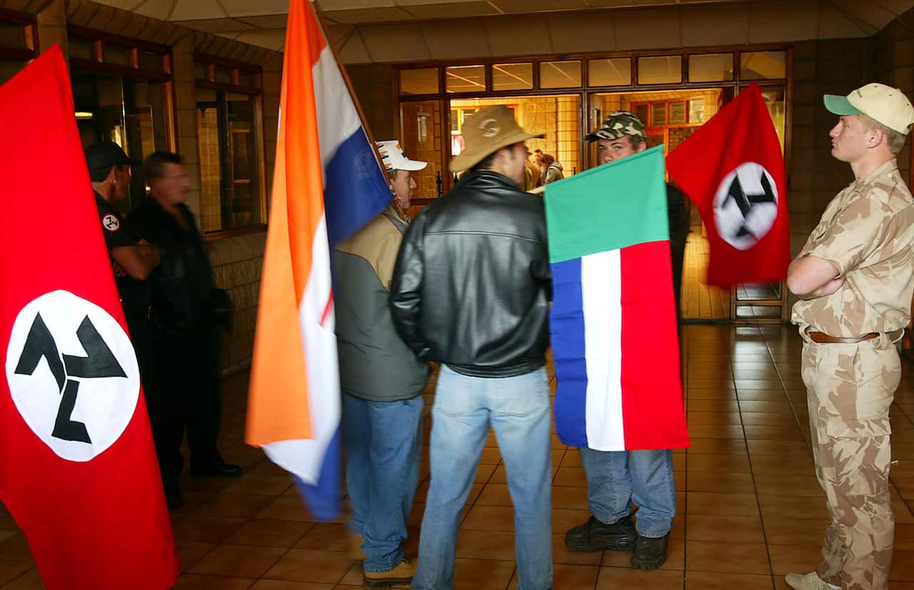 Supporters of the Afrikaner Resistance Movement display an old South African flag, an old Afrikaner "Vierkleur" flag and swastika-like flags in 2004.