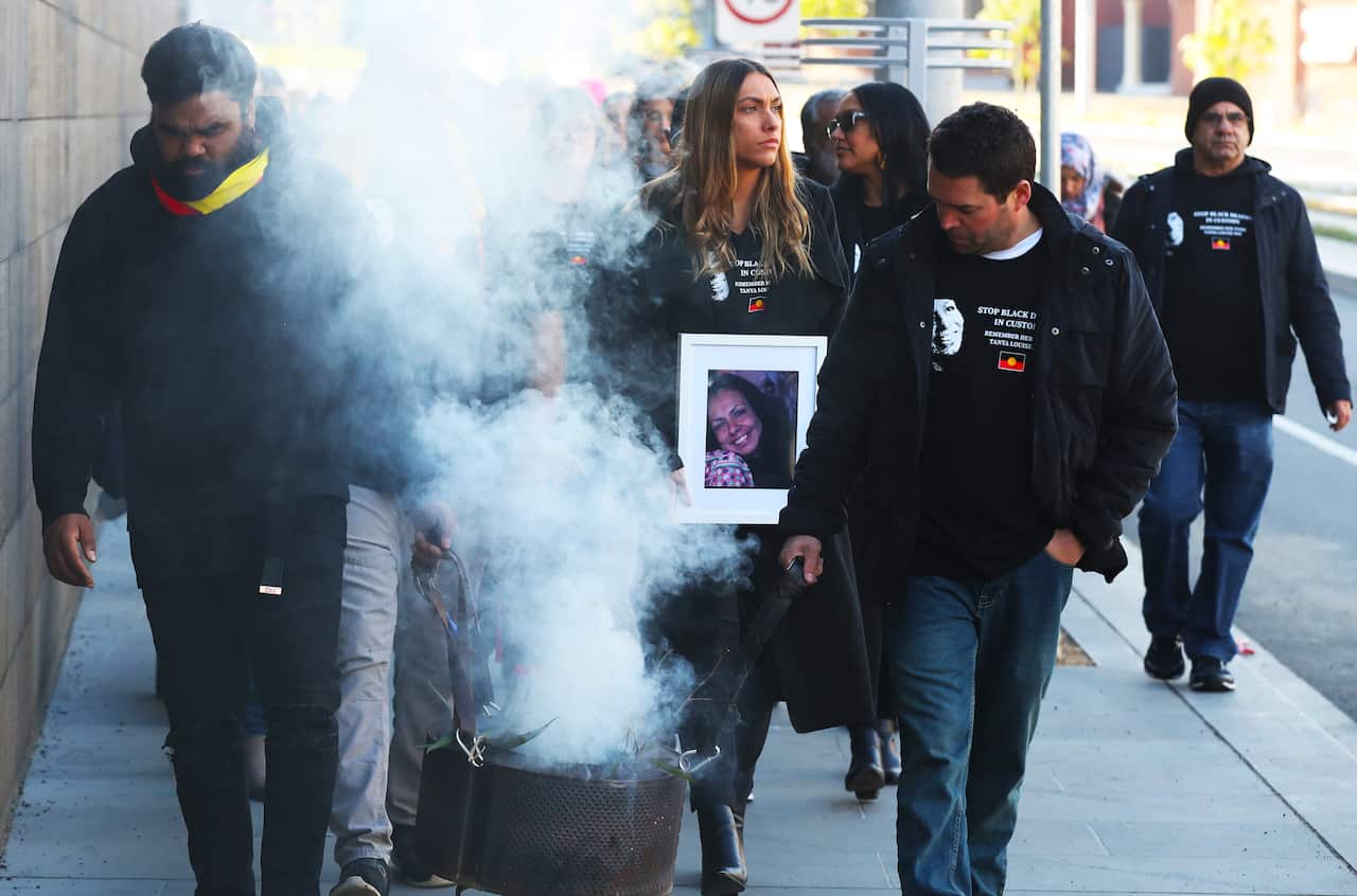 Family members, including Tanya's daughter Apryl Watson (centre), march to the Coroners Court after smoking ceremony in Kings Domain Park.