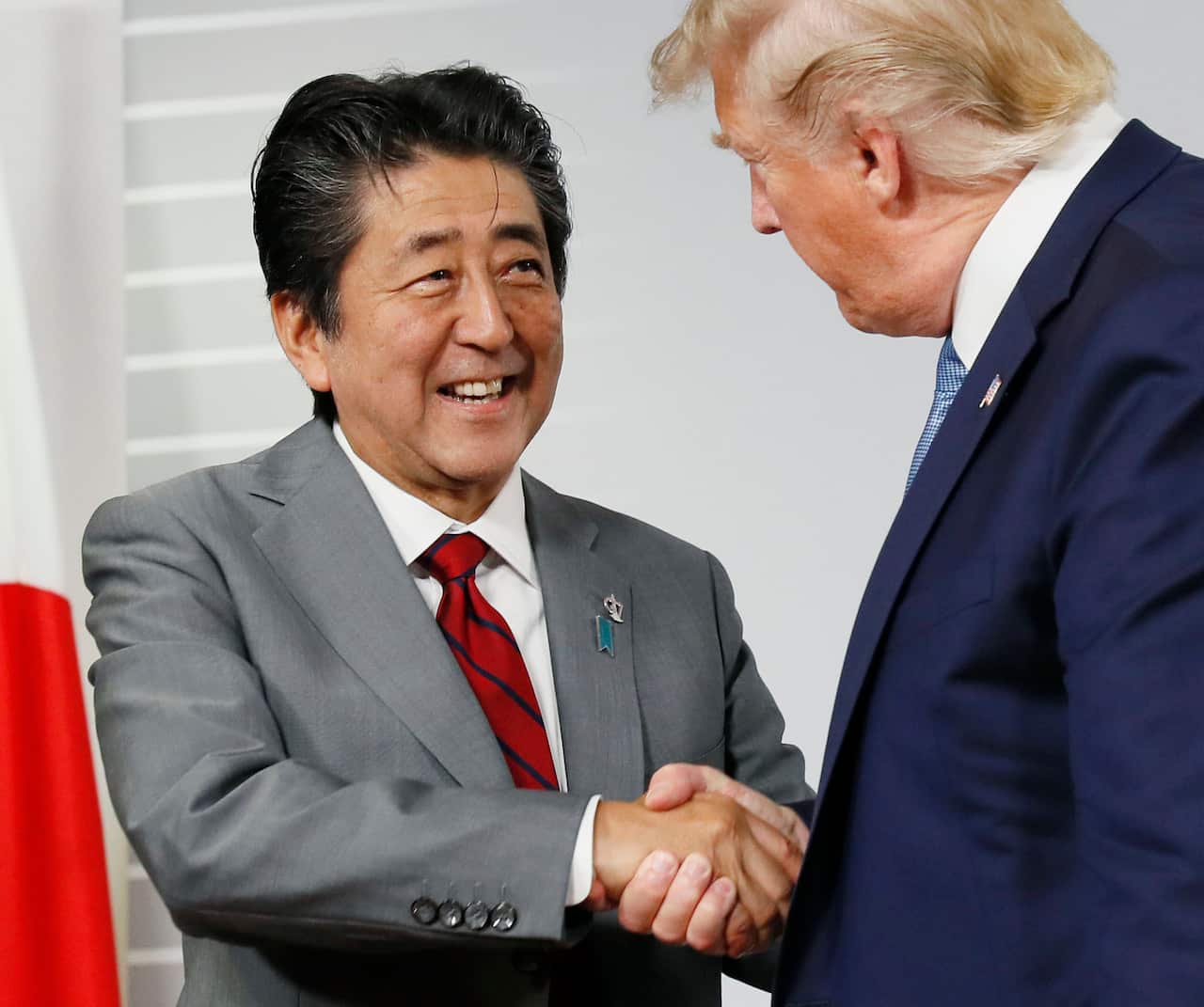 Japanese Prime Minister Shinzo Abe (L) and U.S. President Donald Trump shake hands after their second meeting in Biarritz, southwestern France.