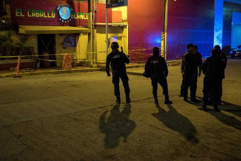 A police officer stands guard in the early hours of the morning in front of the El Caballo Blanco bar