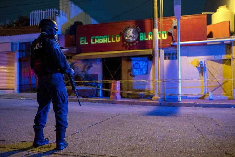 A police officer stands guard in the early hours of the morning in front of the El Caballo Blanco bar