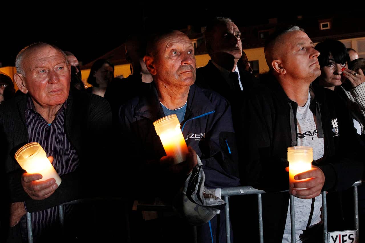 Spectators hold candles in their hands at the memorial service during ceremony marking 80th anniversary of World War II.