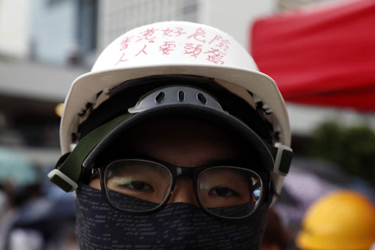 A secondary school student wearing a helmet with the words 'Hong Kong is dangerous, everyone must wear helmets'.