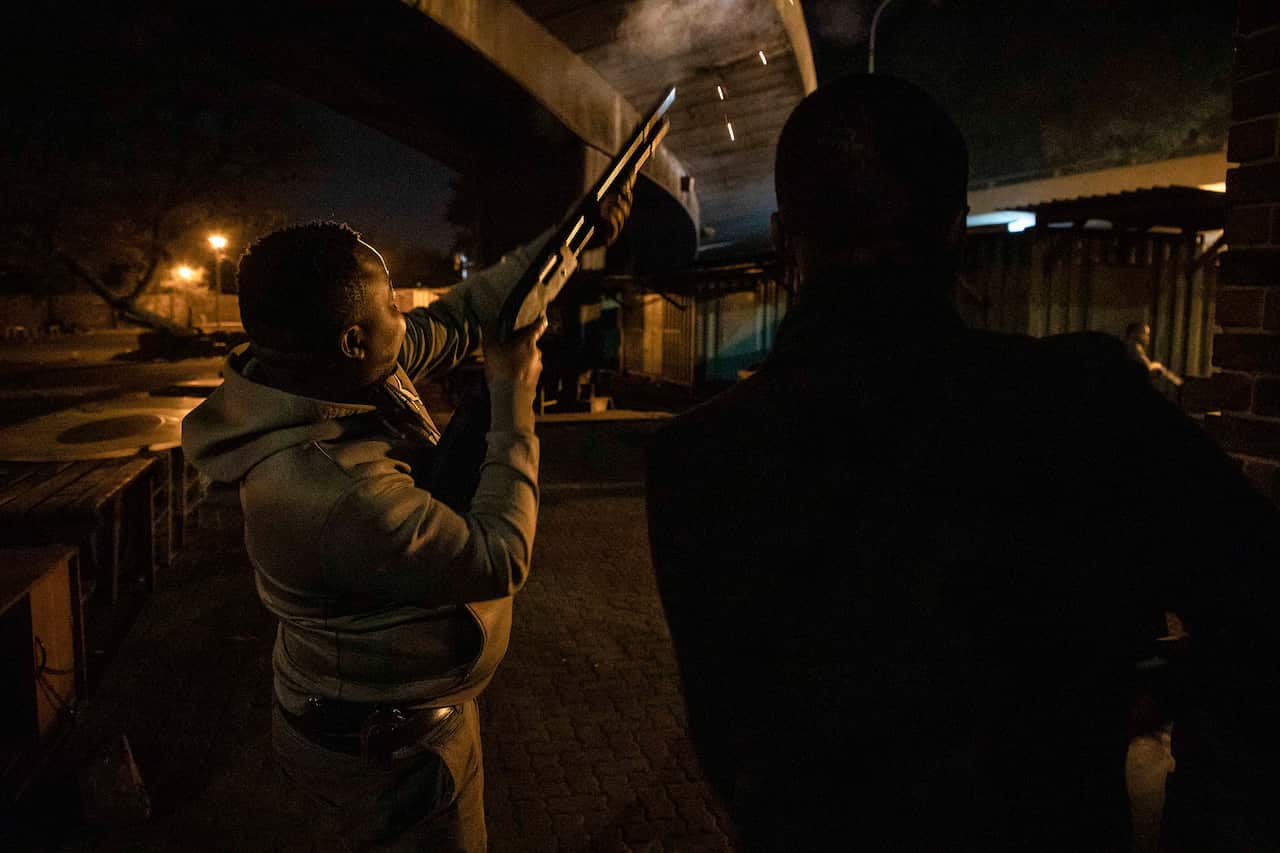 In this photo taken Monday, Sept. 2 2019, police fire rubber bullets at looters in Jeppes Town, Johannesburg CBD.
