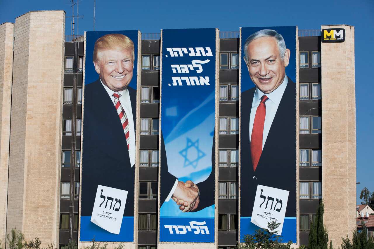 An election campaign billboard of the ruling Likud party shows Israeli Prime Minister Benjamin Netanyahu shaking hands with US President Donald Trump.