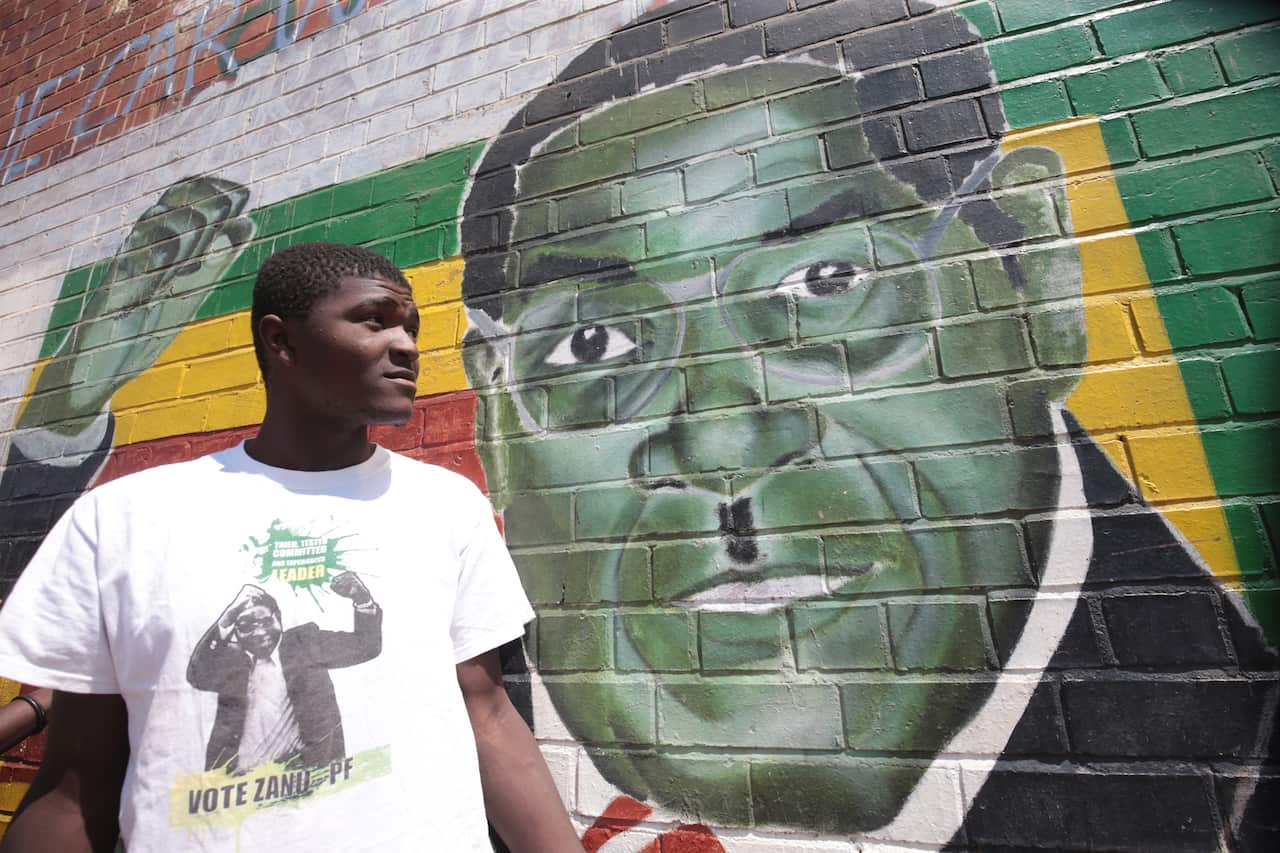A man stands next to a mural depicting former Zimbabwean president Robert Mugabe, in the high density suburb of Mbare, Harare, Zimbabwe.