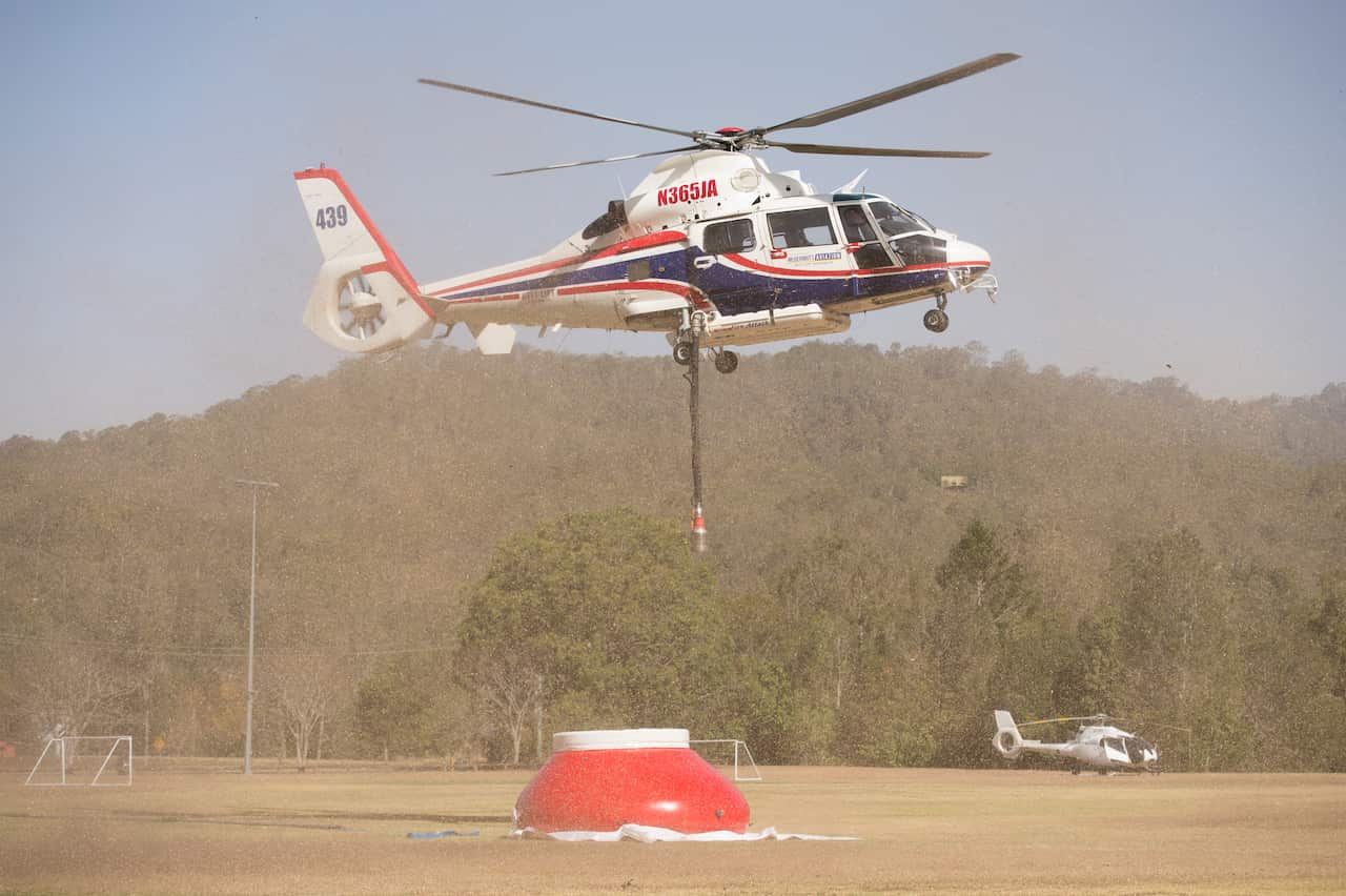 A water tanker helicopter picks up water at Moriarty Park Hall in Canungra, Queensland.