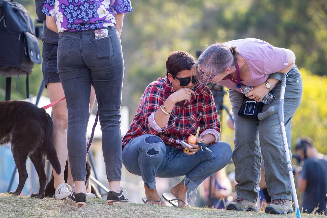 A Canungra fire evacuee is comforted outside Moriarty Park Hall where they attended a community meeting about the fires in the region.
