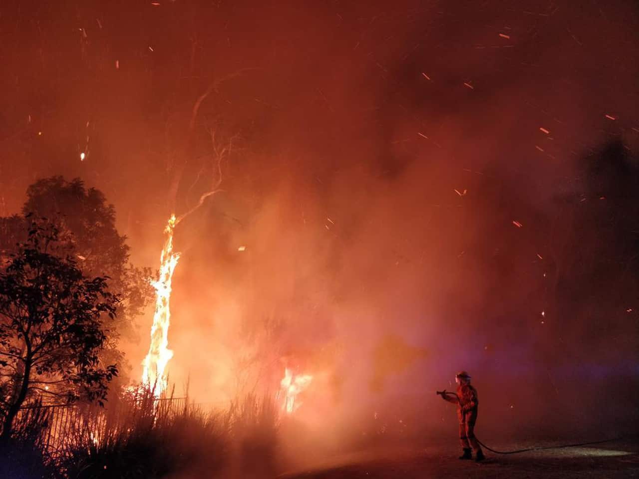 A blaze rages near residences in Peregian Springs on the Sunshine Coast.