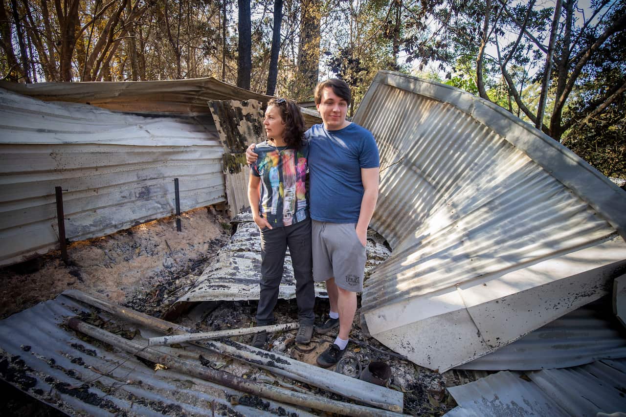 Lisa Groom and her son Luke Beyer stand in the wreckage of a shed on their property on Binna Burra Road, Beechmont.
