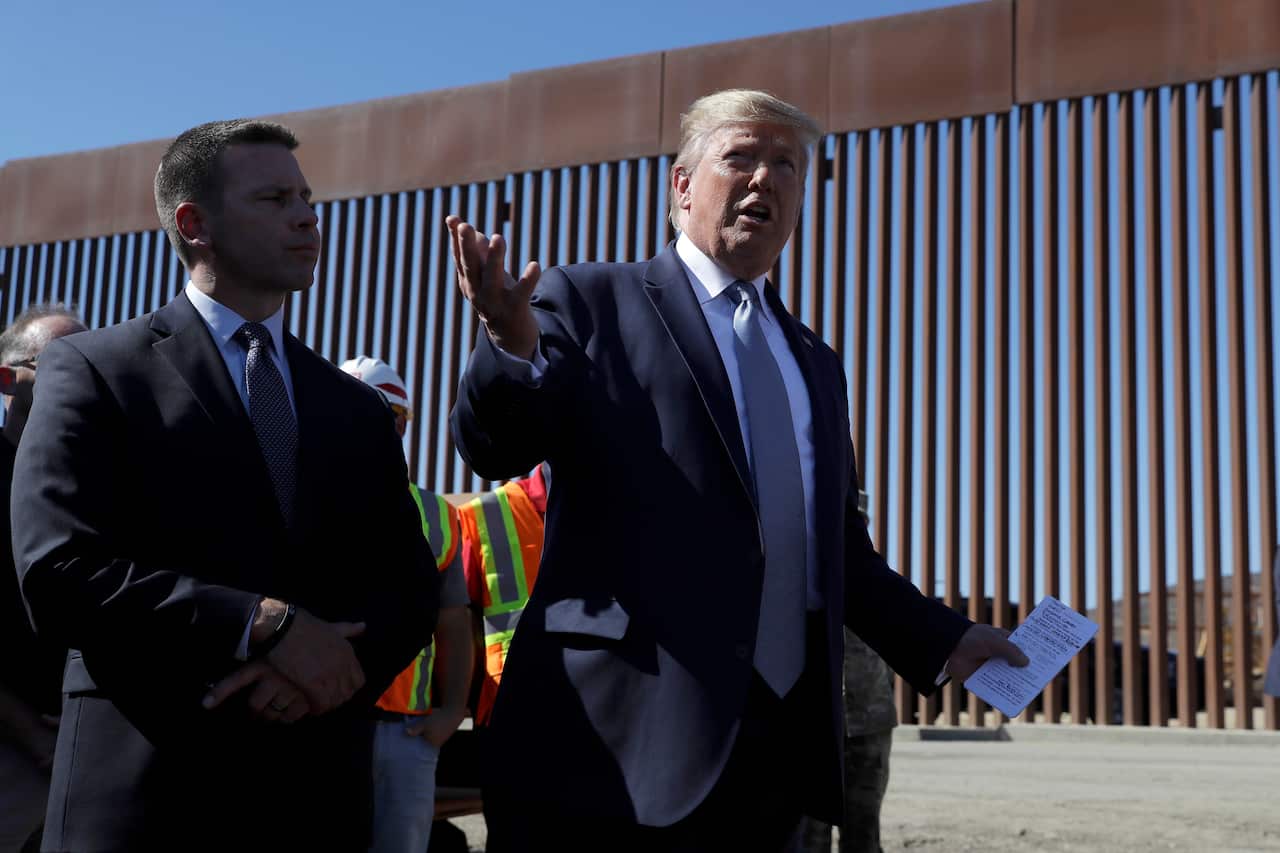 President Donald Trump talks with reporters as he tours a section of the southern border wall, Wednesday, Sept. 18, 2019, in Otay Mesa, Calif., as acting Homeland Secretary Kevin McAleenan listens at left. (AP Photo/Evan Vucci)