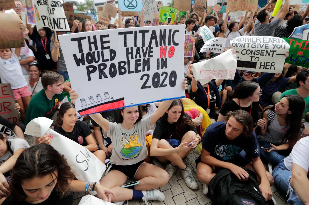 Students hold signs during a protest organized by the Youth Climate Strike outside of Miami Beach City Hall.