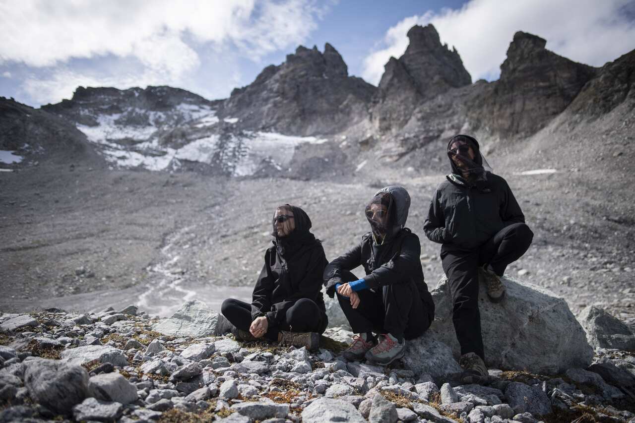 Activists sit in front of the Pizol glacier and mountain during a commemoration for the dying glacier of Pizol mountain.