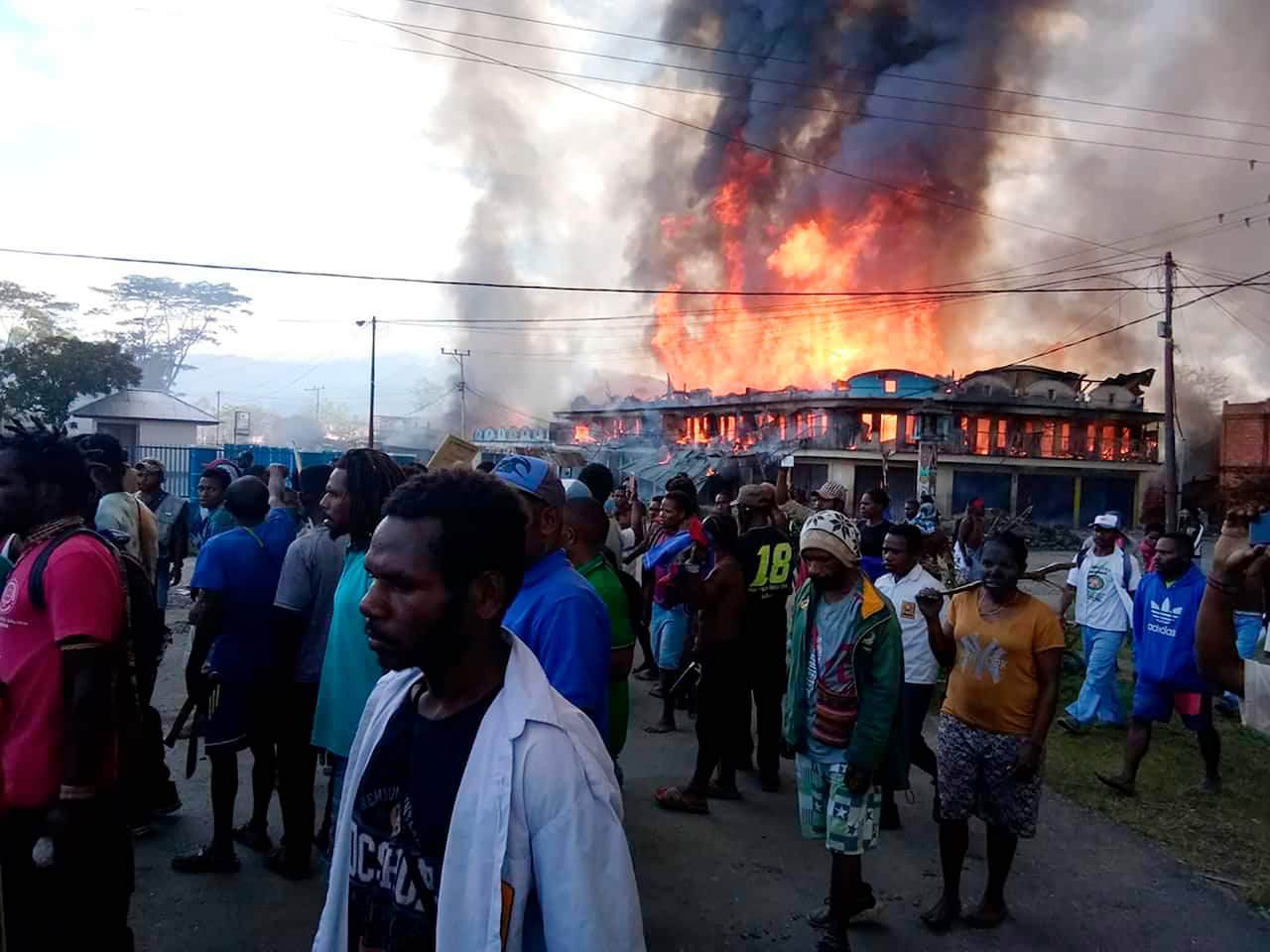 People gather as shops burn in the background during a protest in Wamena on 23 September.
