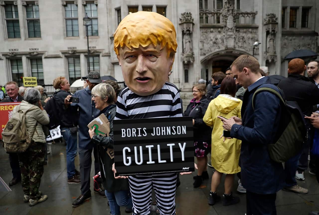 A person dressed as Boris Johnson in a prison uniform stands outside the Supreme Court.