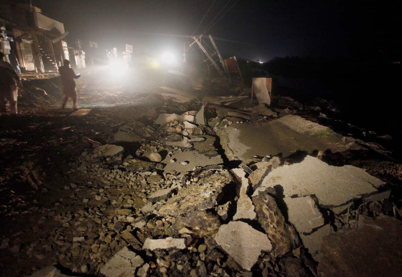 People walk on a road damaged by a powerful earthquake that struck in Jatlan near Mirpur, in northeast Pakistan, Tuesday, Sept. 24, 2019. (AP Photo/Anjum Naveed)