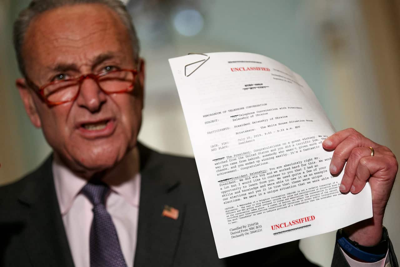 Senator Chuck Schumer holds up a copy of a released transcript of a phone call between President Donald Trump and the President of Ukraine.