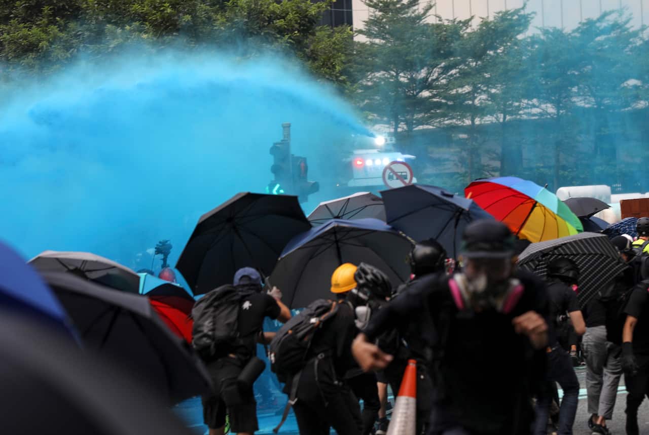 Police fire water canon toward anti-government protesters.