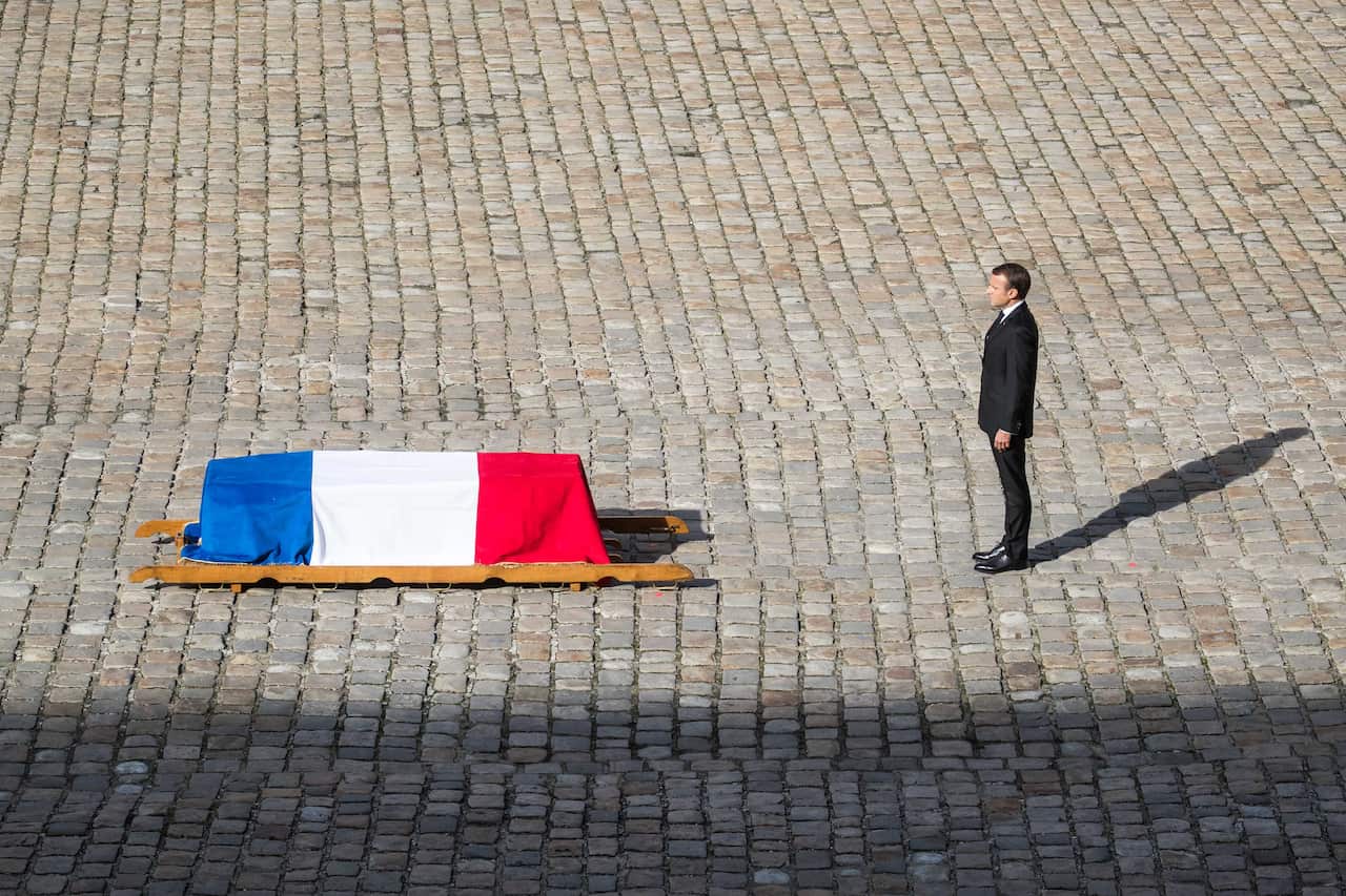 French President Emmanuel Macron pays tribute in front of the flag-draped coffin of the late former French leader Jacques Chirac.