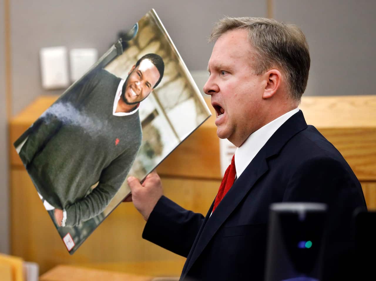 Assistant District Attorney Jason Hermus waves a photo of Botham Jean at the jury as he presents his closing arguments in Amber Guyger's murder trial.