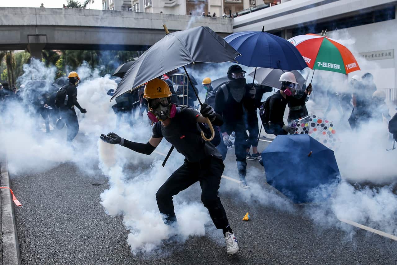 An anti-government protester tosses back a tear gas grenade during protests on National Day in Hong Kong.