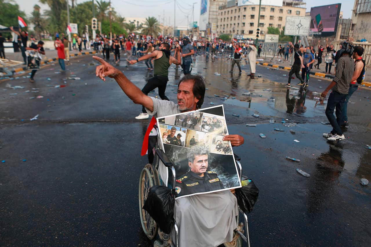 A protester holds a poster of Lieutenant General Abdul-Wahab al-Saadi.