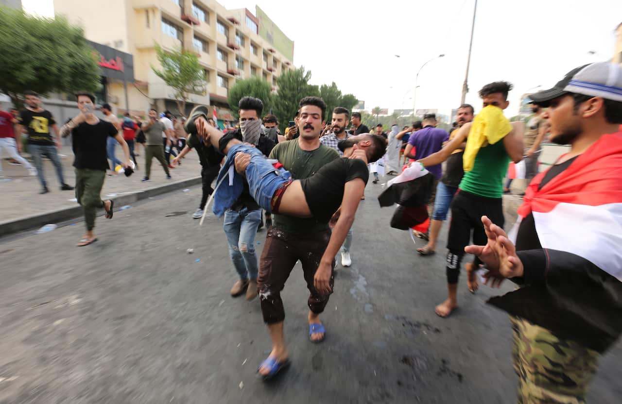 Iraqi protesters carry a wounded man who was injured during a clashes with Iraqi riot forces.