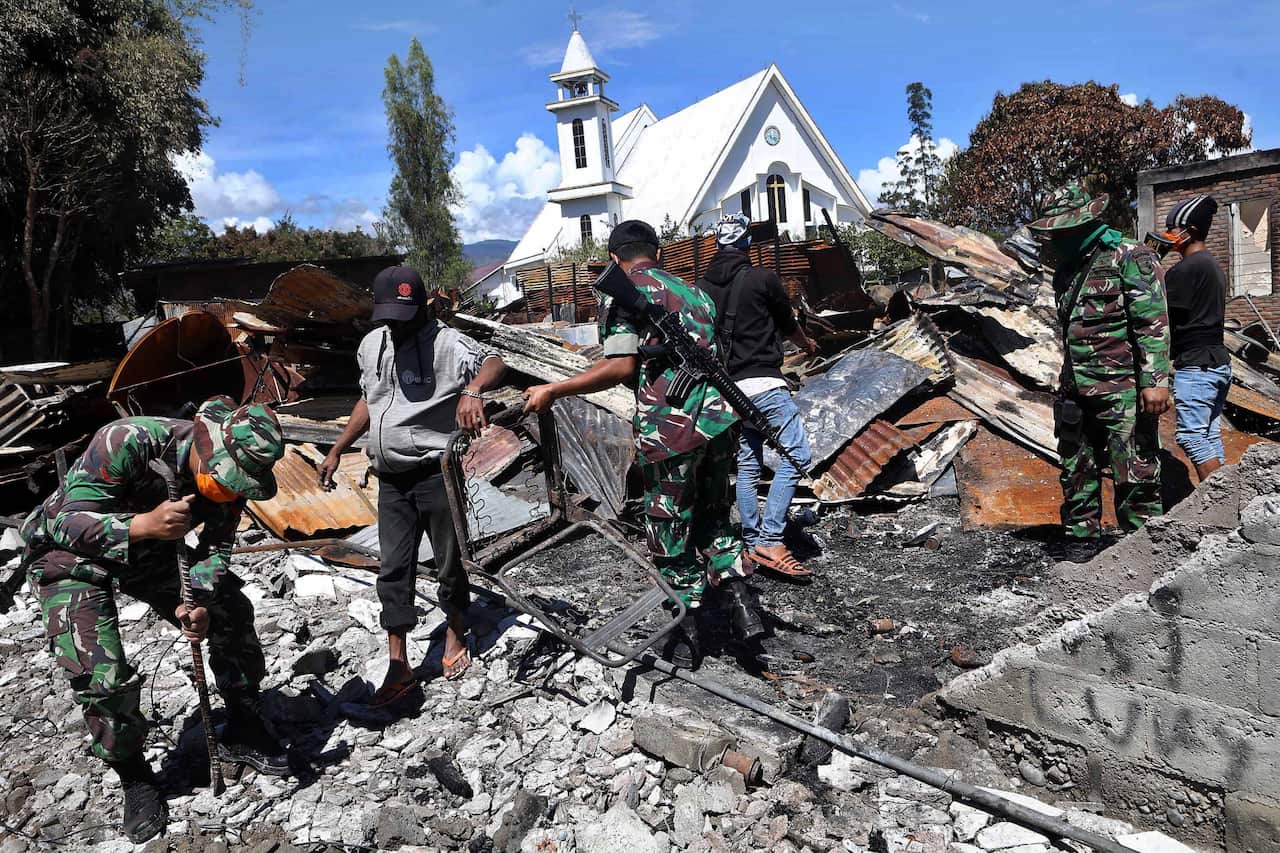 Indonesian security forces and residents clean up the debris of buildings that were torched during recent riots in Wamena, Papua.