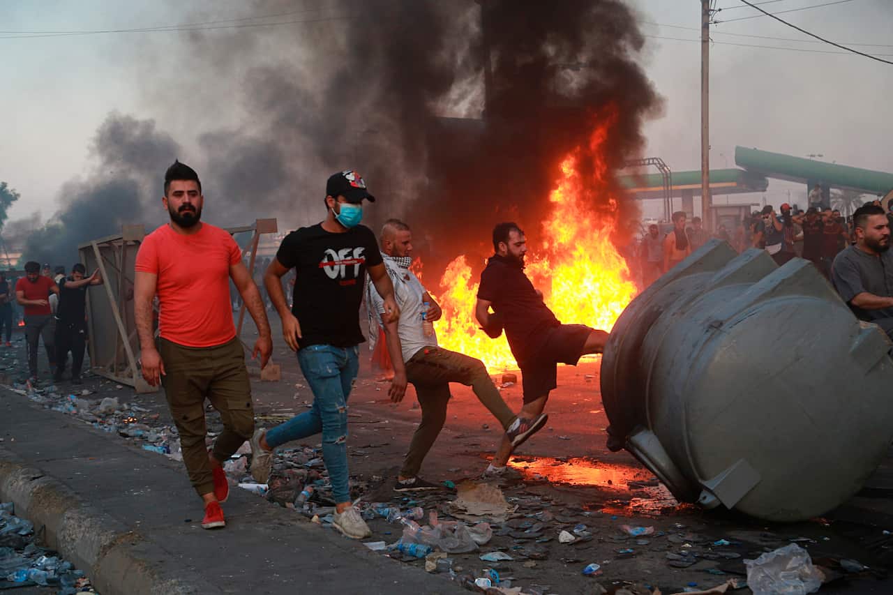 Anti-government protesters set fires and close a street during a demonstration in Baghdad, Iraq.
