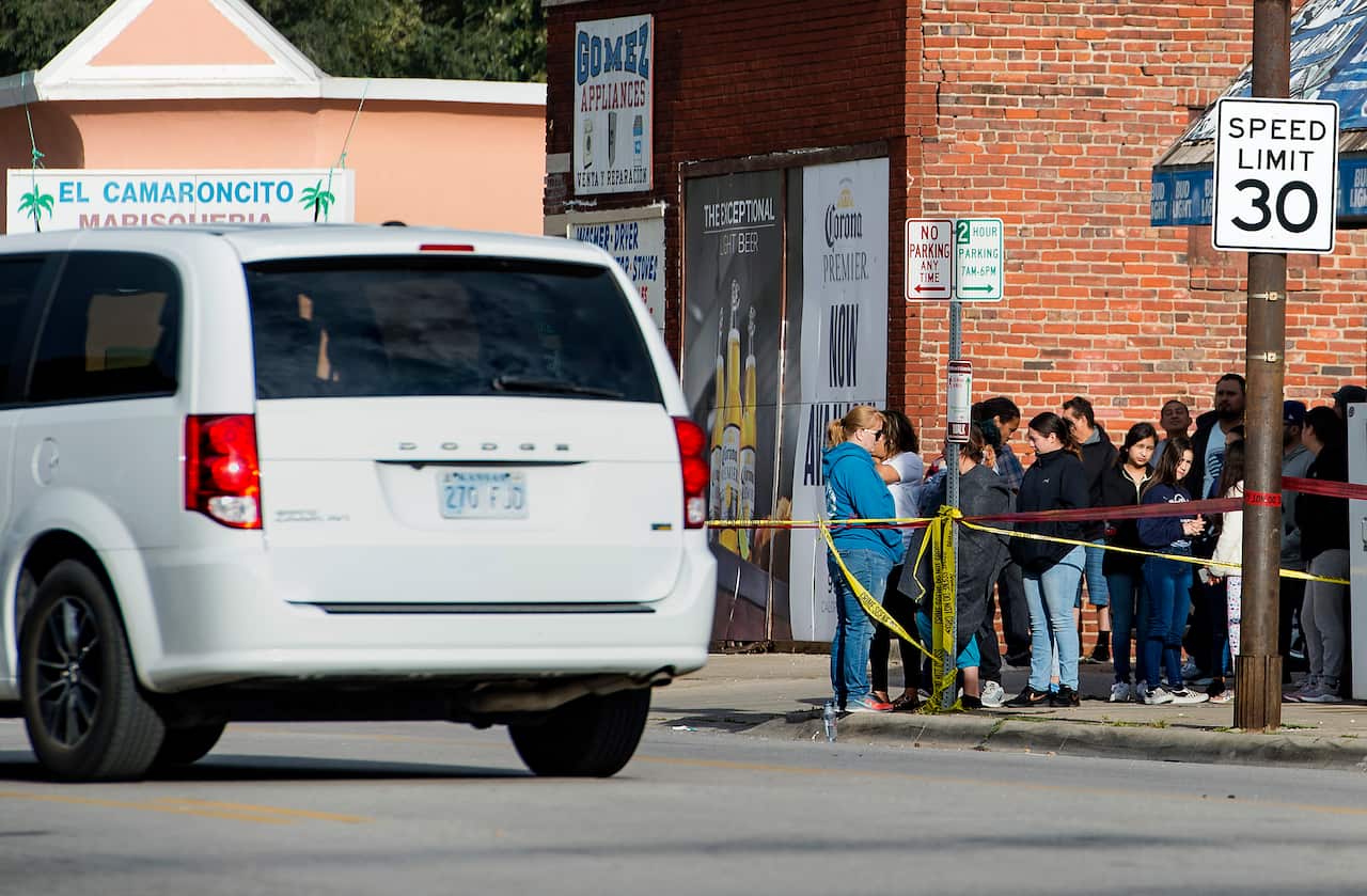 A coroner's van waits to transport a shooting victim as people gather near the scene of a shooting at Tequila KC Bar Sunday, Oct. 6, 2019, in Kansas City, Kan. (Tammy Ljungblad/The Kansas City Star via AP)