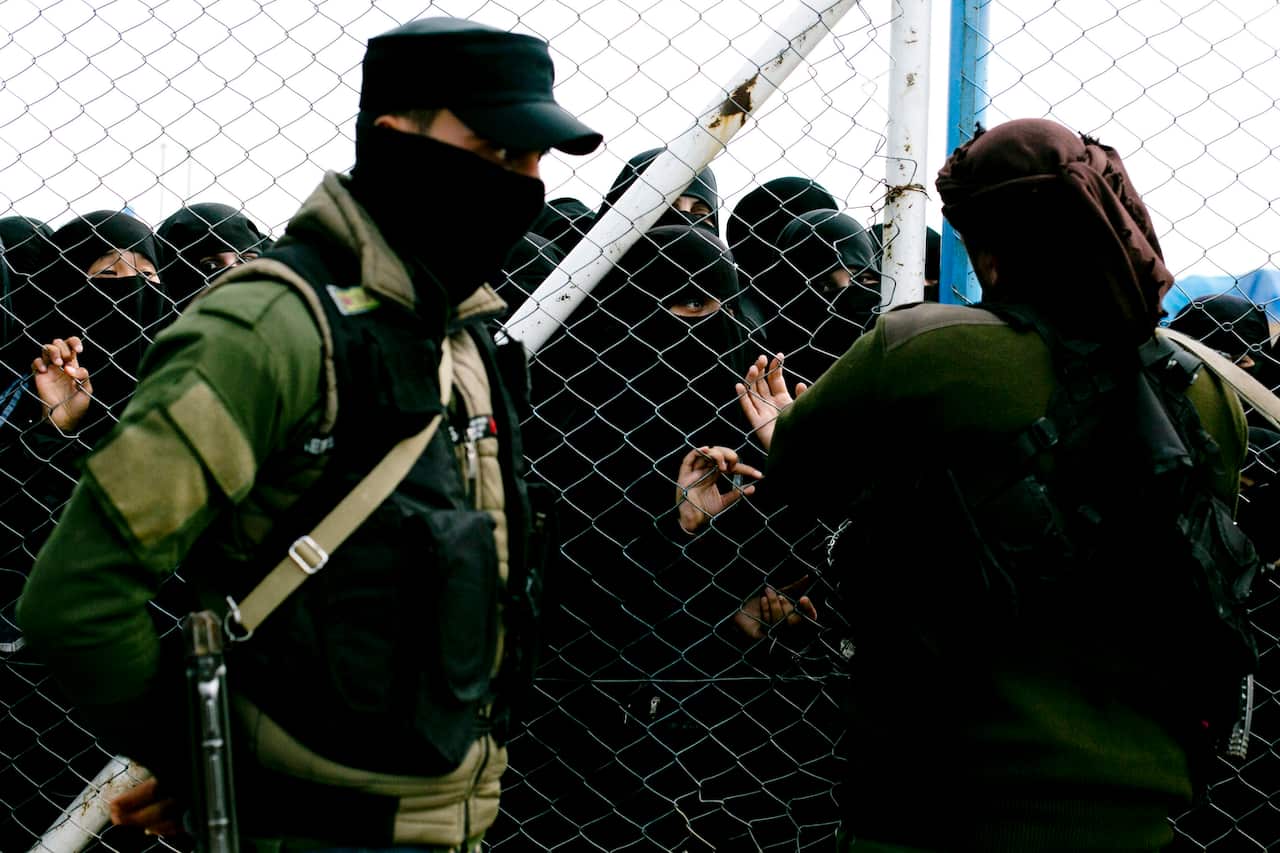 Women speak to guards at the gate that closes off the section for foreign families who lived in the Islamic State's so-called caliphate at Al-Hol camp.