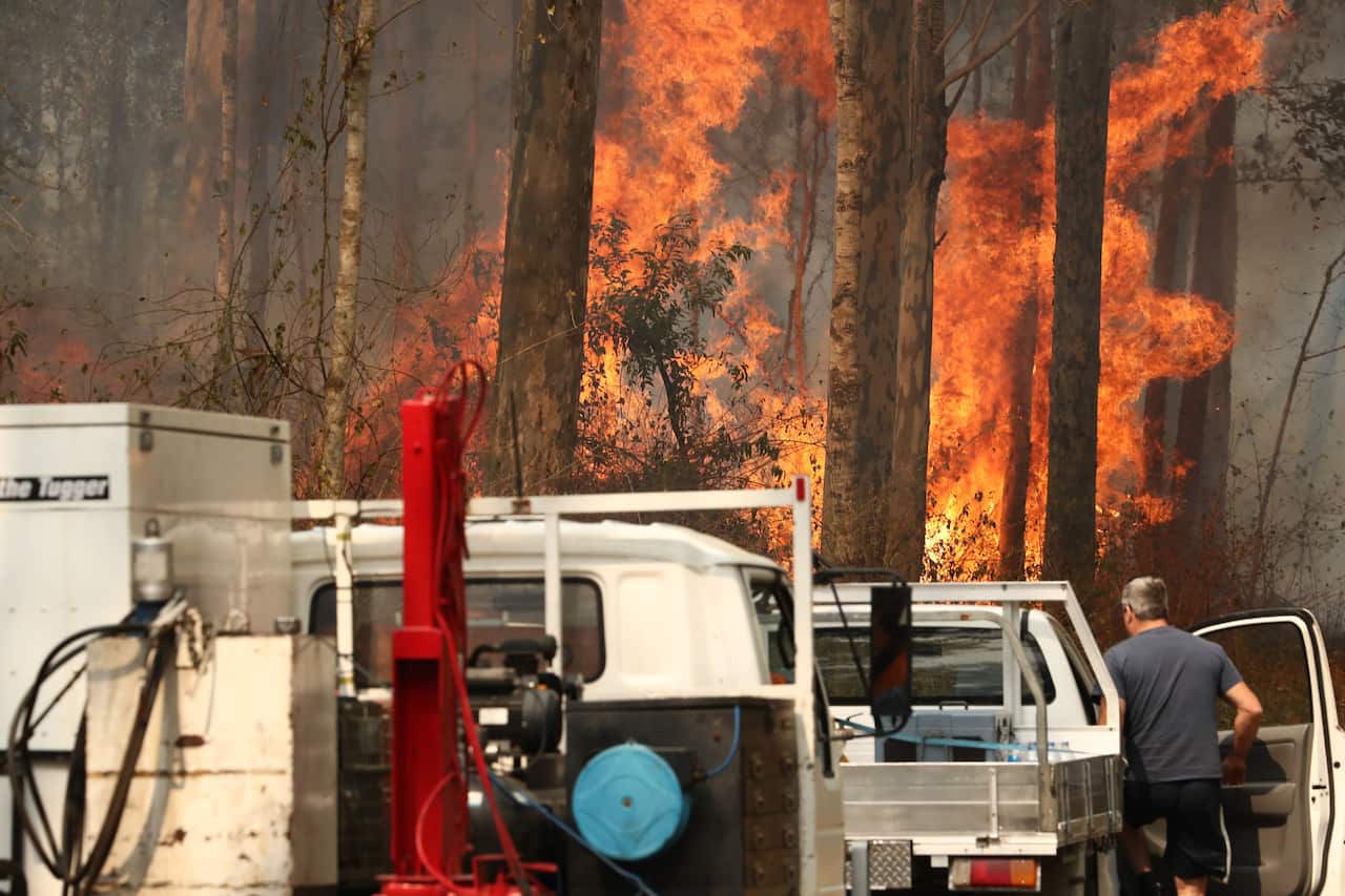 Flames come perilously close to vehicles along a road at Busbys Flat.