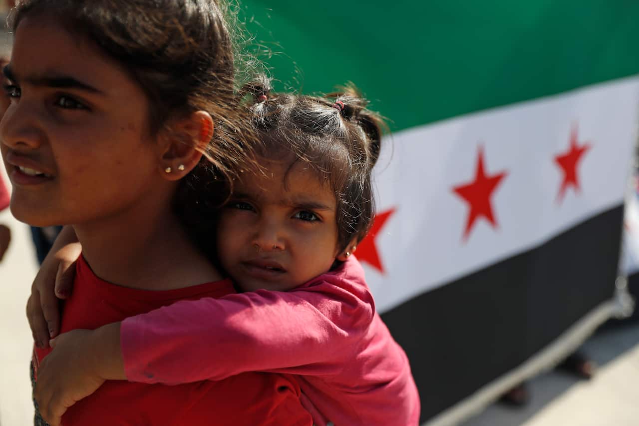 Children walk pas a Syrian revolutionary flag by the Syrian border on the edge of the town of Akcakale, Sanliurfa province, southeastern Turkey.