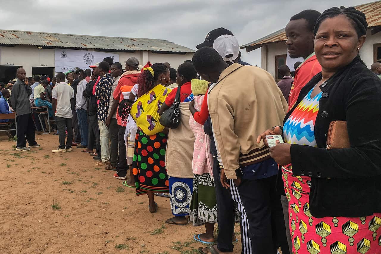 People queue in line as they wait to vote outside a polling station in Chimoio, Manica Province, Mozambique.