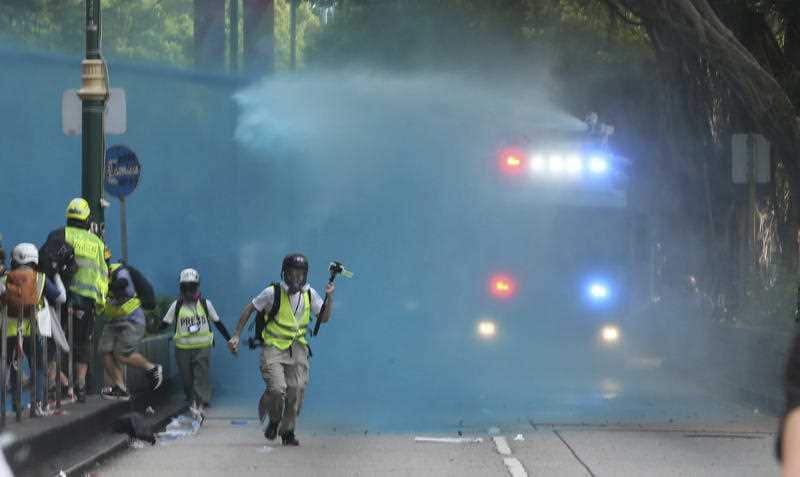 Hong Kong riot police discharge a blue water on protesters